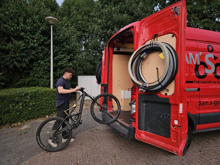 Sam pakt een mountainbike uit de achterkant van zijn bus